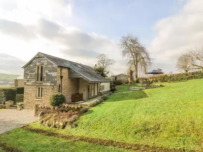 a stone house on a hill with a green field at Woodfield Coach House in Merrymeet