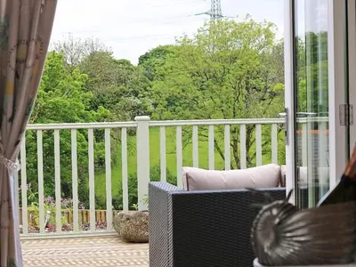 a porch with a white fence and a chair on a balcony at Omalast in Truro