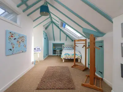 a bedroom with blue ceilings and a bed and a rug at Gwillen in Mawgan Porth