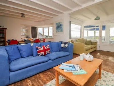 a living room with a blue couch and a table at Gwillen in Mawgan Porth