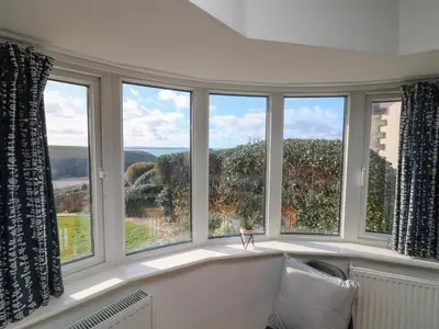 a large window with a white couch in front of it at Gwillen in Mawgan Porth