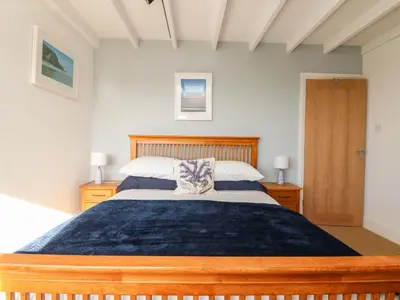 a bedroom with a large bed with a wooden headboard at Gwillen in Mawgan Porth