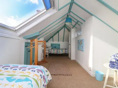 a bedroom with a bed and a window at Gwillen in Mawgan Porth