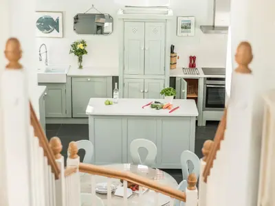 a kitchen with white cabinets and a table and a sink at The Barn at Little Resugga in Bugle