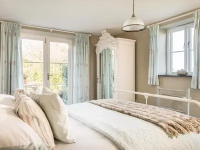 a white bed in a room with windows at The Barn at Little Resugga in Bugle