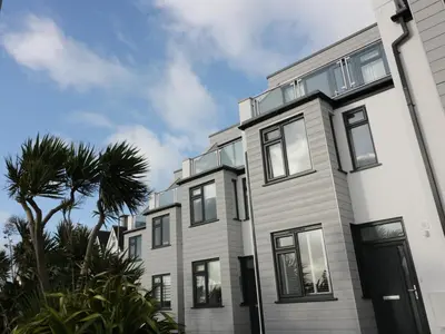 a white building with black windows and a palm tree at Fistral Breeze in Newquay
