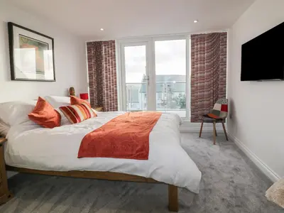 a bedroom with a large bed and a large window at Fistral Breeze in Newquay