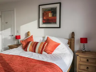 a white bed with orange pillows and a picture on the wall at Fistral Breeze in Newquay