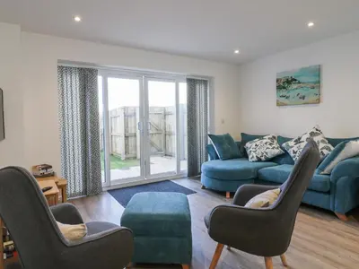 a living room with a blue couch and chairs at Fistral Breeze in Newquay