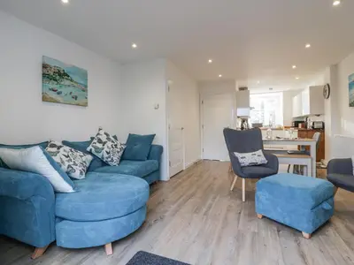 a living room with two blue couches and a kitchen at Fistral Breeze in Newquay