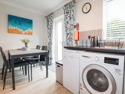 a kitchen with a washing machine and a table at Gull Cottage in Padstow