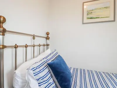 a bedroom with a bed with blue and white pillows at Gull Cottage in Padstow
