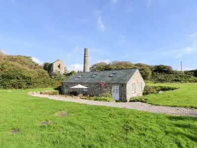 an old stone house in a grassy field with a chimney at Wheal Grey in Germoe