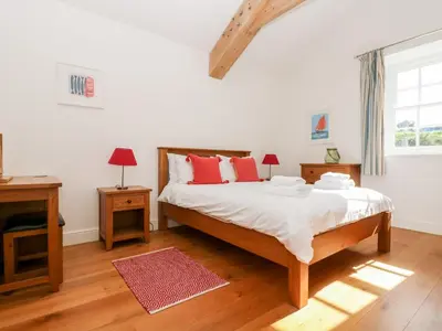 a bedroom with a bed with white sheets and red pillows at Wheal Grey in Germoe