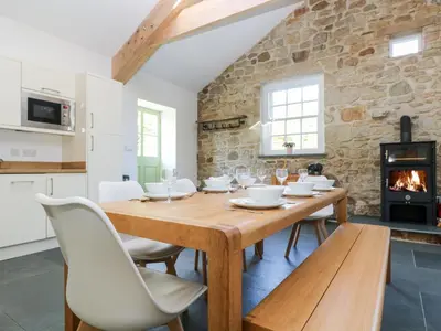 a dining room with a table and chairs and a fireplace at Wheal Grey in Germoe
