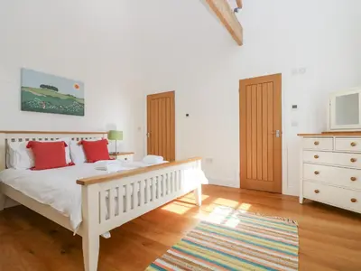 a bedroom with a white bed with red pillows at Wheal Grey in Germoe