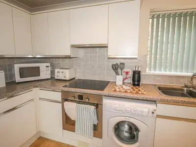 a kitchen with white cabinets and a dishwasher at Kingfisher House in Tintagel