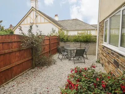 a backyard with a table and chairs and a fence at Kingfisher House in Tintagel