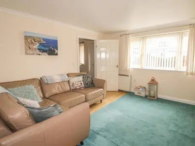 a living room with a brown couch and a blue rug at Kingfisher House in Tintagel