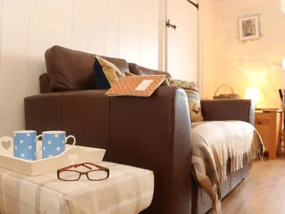 a living room with a brown couch and a table at Ner Sea in Marazion