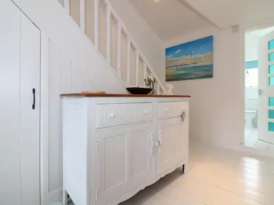 a white chest of drawers in a hallway with stairs at Ner Sea in Marazion