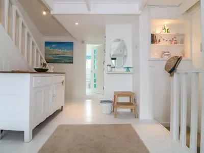 a white hallway with a table and a stool at Ner Sea in Marazion