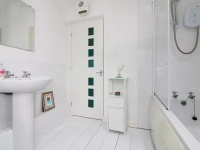 a white bathroom with a sink and a bath tub at Ner Sea in Marazion