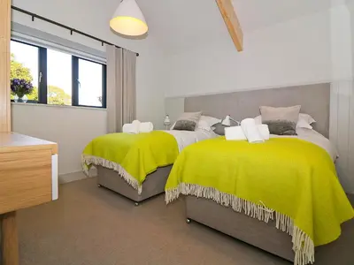 a bedroom with two beds with yellow blankets at Pig House, Boskensoe Barns in Helford Passage