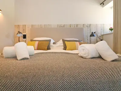 a large bed with white pillows on top of it at Pig House, Boskensoe Barns in Helford Passage