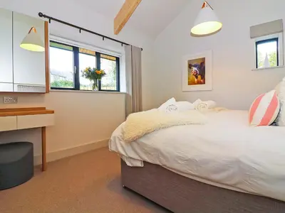 a bedroom with a bed and a desk and windows at Pig House, Boskensoe Barns in Helford Passage