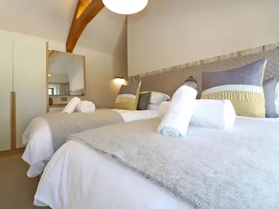 a bedroom with two beds and a mirror at Long House, Boskensoe Barns in Helford Passage