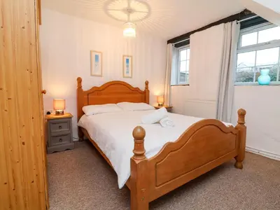 a bedroom with a wooden bed and a window at Threshings Cottage in Tintagel