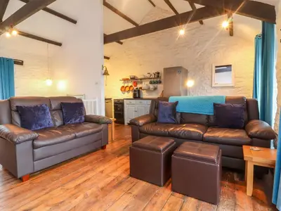 a living room with two leather couches and a kitchen at Threshings Cottage in Tintagel