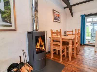 a fireplace in a room with a table and a dining room at Threshings Cottage in Tintagel