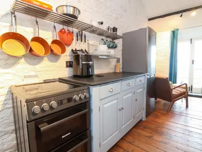 a kitchen with a stove and some pots and pans at Threshings Cottage in Tintagel