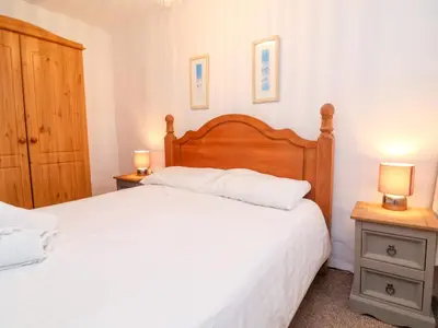 a bedroom with a large bed and two night stands at Threshings Cottage in Tintagel