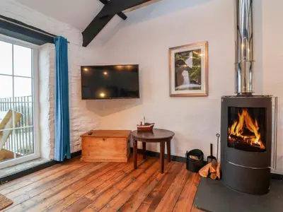 a living room with a fireplace and a table at Threshings Cottage in Tintagel