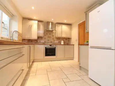 a kitchen with white cabinets and a tile floor at Chy Kerris, Carbis Bay in Carbis Bay