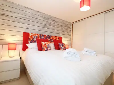a bedroom with a large white bed with red pillows at Chy Kerris, Carbis Bay in Carbis Bay