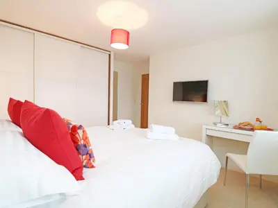 a bedroom with a white bed with red pillows at Chy Kerris, Carbis Bay in Carbis Bay