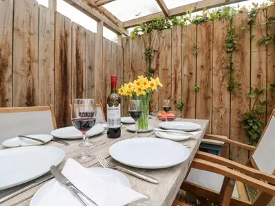a wooden table with white plates and wine glasses at Chy Kerris, Carbis Bay in Carbis Bay