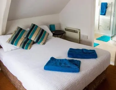 a bed with two blue towels on top of it at Drang house all rooms have stairs in Padstow