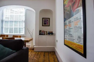 a living room with a couch and a poster on the wall at Drang house all rooms have stairs in Padstow