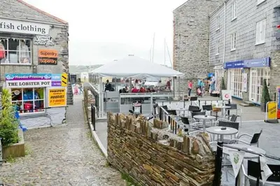 a cafe with tables and an umbrella on a street at Drang house all rooms have stairs in Padstow
