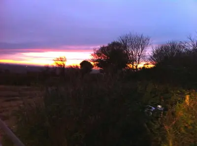 a person in a field with the sunset in the background at Demelza Cottage Apartment in Bodmin