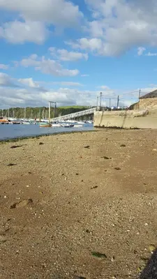 a beach with boats in the water and a bridge at Polmarine in Polruan