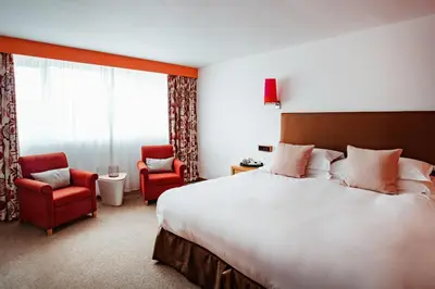 a hotel room with a large bed and two chairs at Bedruthan Hotel & Spa in Newquay