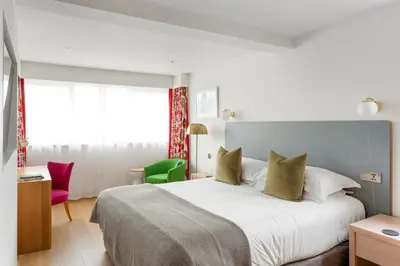 a bedroom with a large bed and a green chair at Bedruthan Hotel & Spa in Newquay