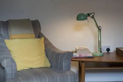 a green lamp sitting on a table next to a couch at Fernleigh Cottage in Boscastle