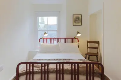 a bed in a room with a window and a chair at Fernleigh Cottage in Boscastle